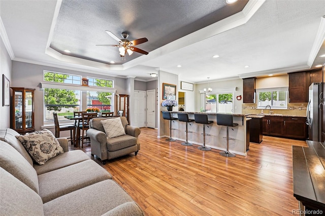 6231 Indian Paintbrush St Unit 214, Frederick, CO 80530 - living room with a tray ceiling, light wood-type flooring, ceiling fan, ornamental molding, and a chandelier