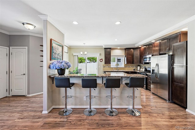 6231 Indian Paintbrush St Unit 214, Frederick, CO 80530 - kitchen featuring stainless steel appliances, dark brown cabinetry, a kitchen breakfast bar, light stone countertops, and a peninsula