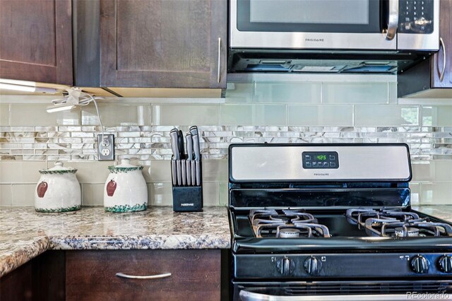 6231 Indian Paintbrush St Unit 214, Frederick, CO 80530 - kitchen featuring appliances with stainless steel finishes, dark brown cabinets, backsplash, and light stone counters
