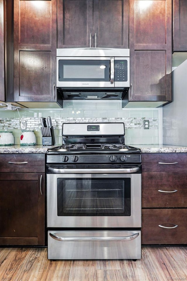 6231 Indian Paintbrush St Unit 214, Frederick, CO 80530 - kitchen featuring stainless steel appliances, light wood-type flooring, dark brown cabinetry, and light stone countertops