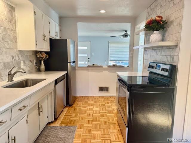 kitchen featuring tasteful backsplash, sink, light parquet floors, white cabinetry, and appliances with stainless steel finishes