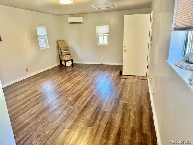 spare room featuring a wall unit AC and dark hardwood / wood-style floors