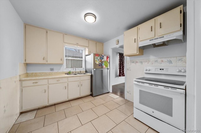 kitchen featuring stainless steel fridge, white range with electric stovetop, sink, cream cabinets, and light tile patterned flooring