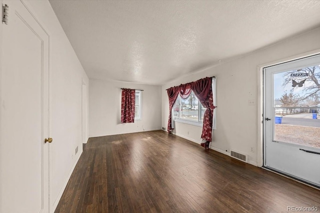 unfurnished room with dark wood-type flooring and a textured ceiling