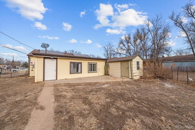 back of house with an outbuilding, a patio, and solar panels