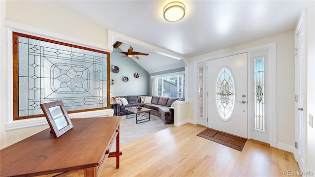 foyer entrance with a ceiling fan, visible vents, baseboards, lofted ceiling, and light wood-style flooring