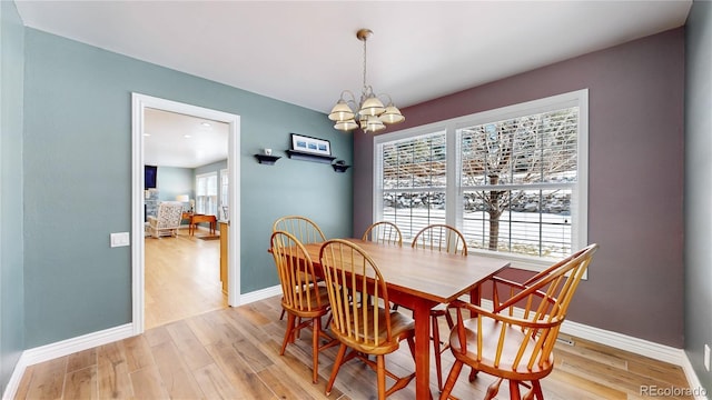 dining room with a notable chandelier, light wood-type flooring, and baseboards