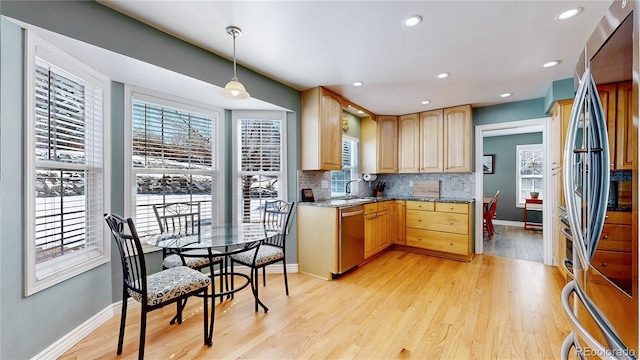 kitchen featuring decorative backsplash, light wood finished floors, plenty of natural light, and appliances with stainless steel finishes