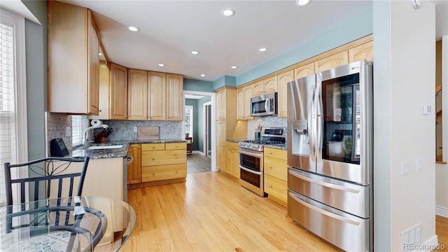 kitchen with a sink, appliances with stainless steel finishes, light wood-style flooring, and light brown cabinets