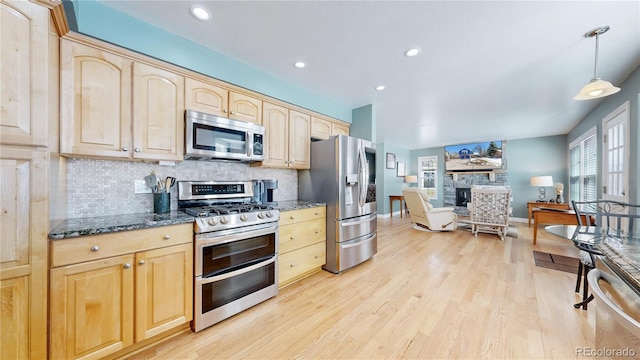 kitchen featuring a stone fireplace, tasteful backsplash, appliances with stainless steel finishes, and light brown cabinetry