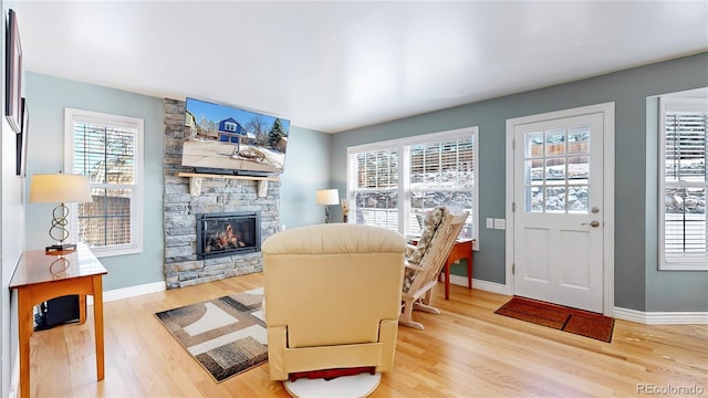 living room with a fireplace, light wood-type flooring, and baseboards