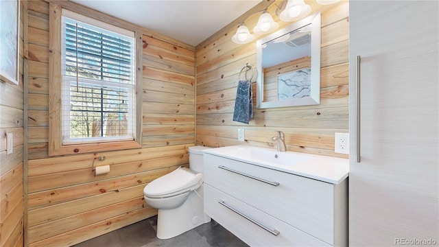 bathroom with wooden walls, toilet, and vanity