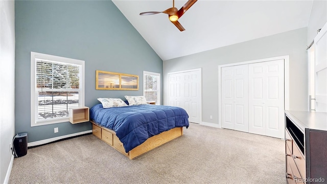 bedroom featuring multiple closets, high vaulted ceiling, a ceiling fan, baseboards, and light colored carpet