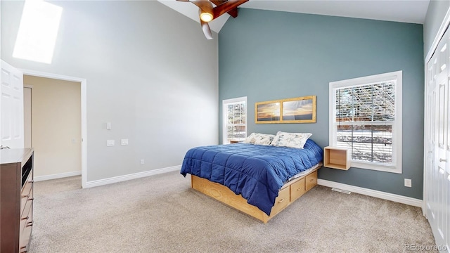 bedroom featuring baseboards, light carpet, high vaulted ceiling, and a ceiling fan