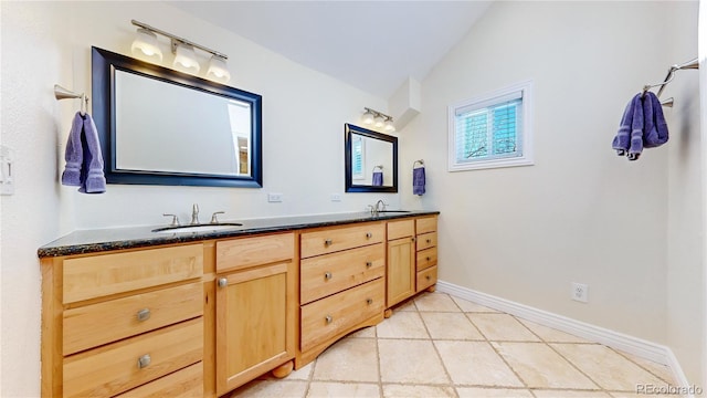 bathroom with lofted ceiling, double vanity, baseboards, and a sink