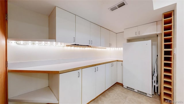 kitchen with visible vents, light tile patterned flooring, freestanding refrigerator, light countertops, and white cabinetry