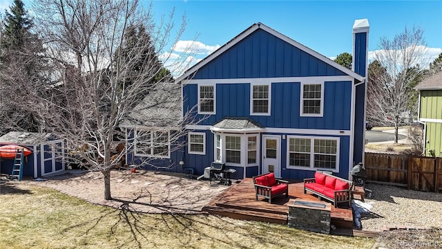 rear view of house featuring board and batten siding, fence, an outdoor hangout area, an outdoor structure, and a storage unit