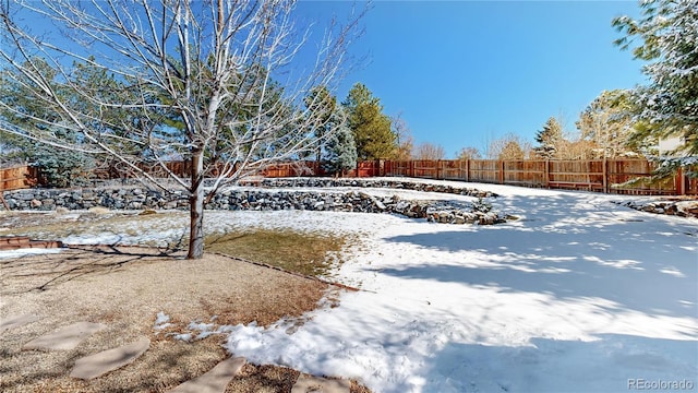 snowy yard featuring a fenced backyard