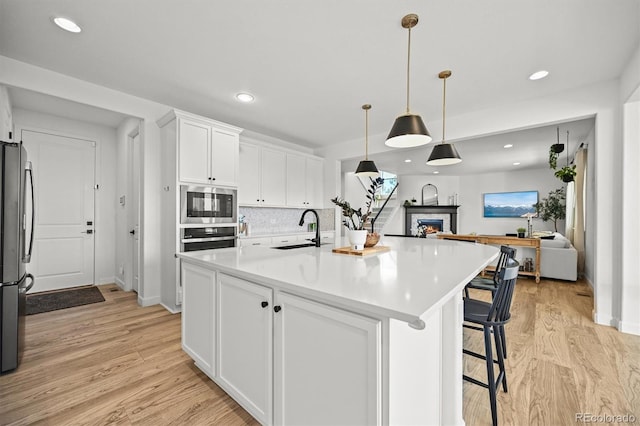 5078 S Quail St, Littleton, CO 80127 - kitchen with stainless steel appliances, light wood-type flooring, open floor plan, white cabinetry, and recessed lighting