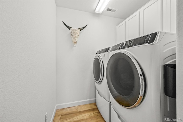 5078 S Quail St, Littleton, CO 80127 - laundry room with washer and clothes dryer, cabinet space, and light wood-style flooring
