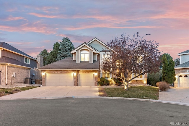 view of front facade featuring an attached garage, brick siding, driveway, and central AC