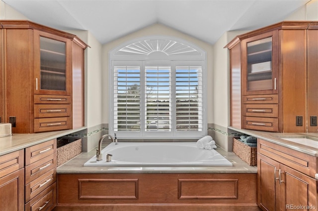 bathroom with vanity, a bath, and vaulted ceiling