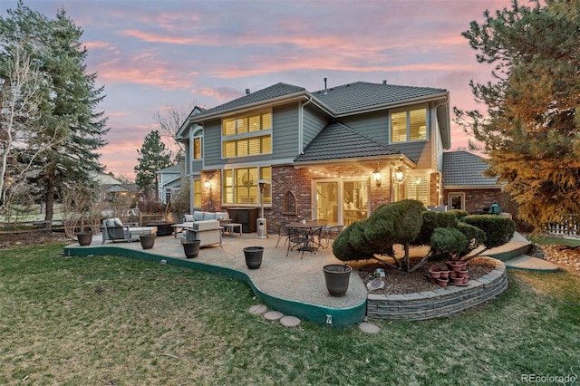 back of property featuring a patio area, brick siding, a yard, a tile roof, and an outdoor living space