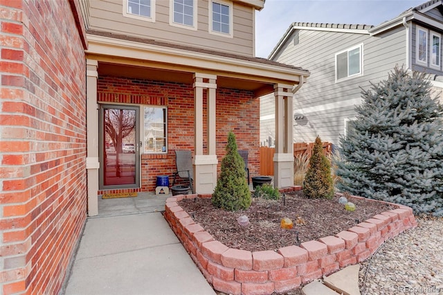 entrance to property with covered porch and brick siding