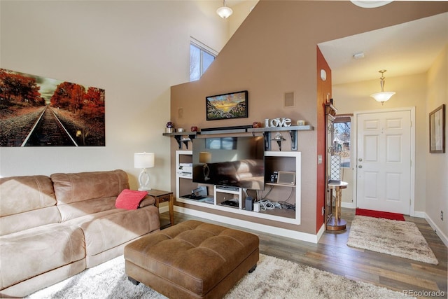 living area featuring a towering ceiling, visible vents, baseboards, and wood finished floors