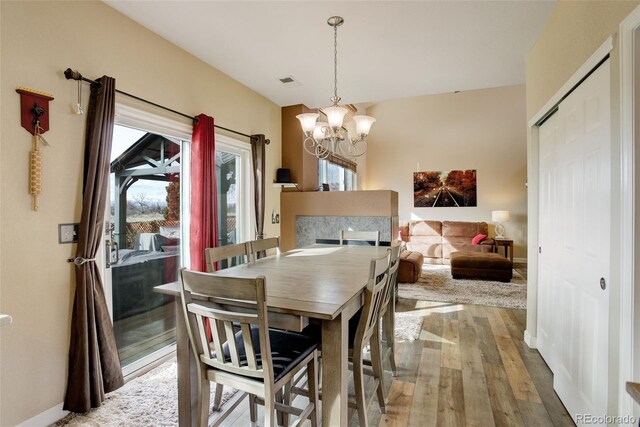 dining area featuring a chandelier, hardwood / wood-style floors, visible vents, and baseboards