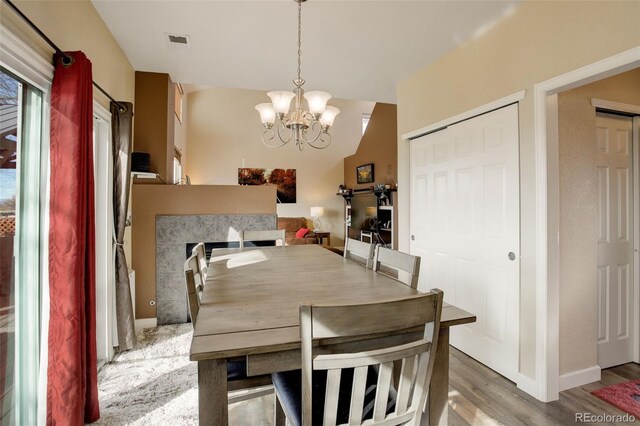 dining space featuring baseboards, visible vents, light wood finished floors, and an inviting chandelier