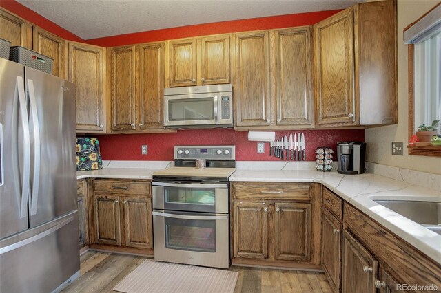 kitchen with stainless steel appliances, light wood-type flooring, and brown cabinets