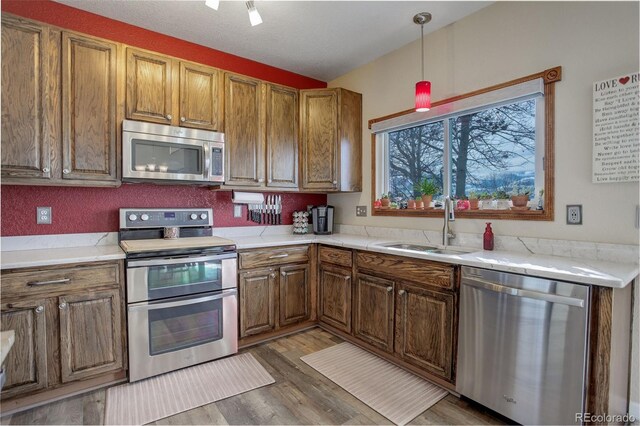 kitchen featuring appliances with stainless steel finishes, light wood-type flooring, light countertops, and a sink