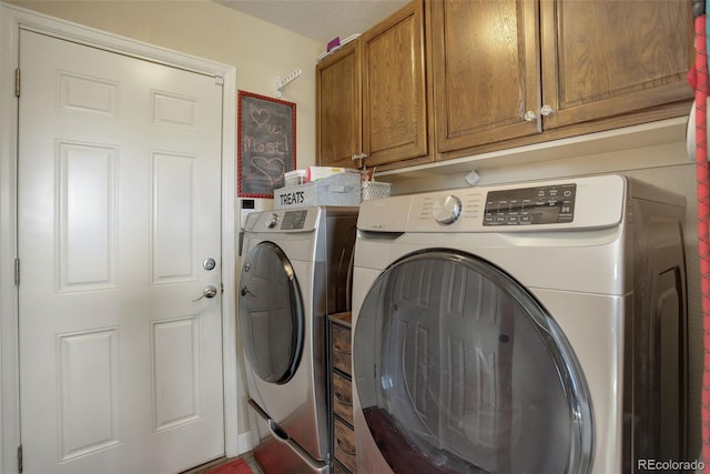 clothes washing area featuring cabinet space and washer and clothes dryer