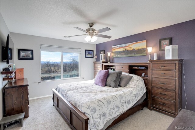 bedroom with light carpet, a textured ceiling, a ceiling fan, and baseboards