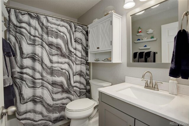 full bath with toilet, vanity, and a textured wall