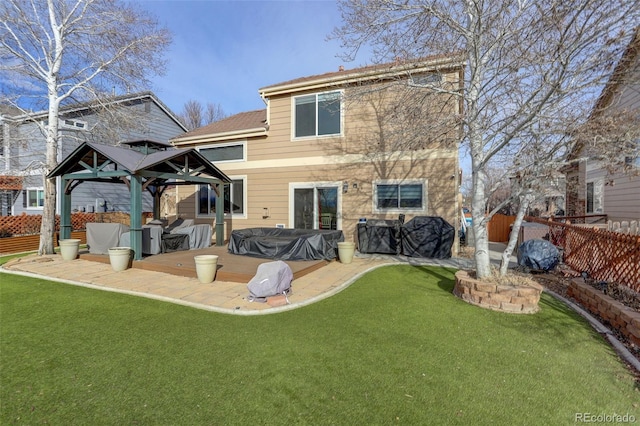 rear view of house with fence, a gazebo, and a lawn