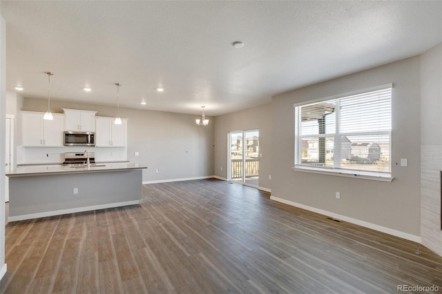 unfurnished living room with sink, a notable chandelier, dark hardwood / wood-style floors, and a textured ceiling