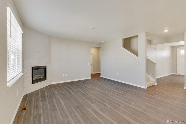 unfurnished living room featuring a tiled fireplace and hardwood / wood-style floors