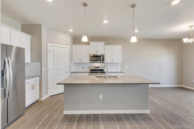 kitchen with white cabinetry, appliances with stainless steel finishes, sink, and an island with sink