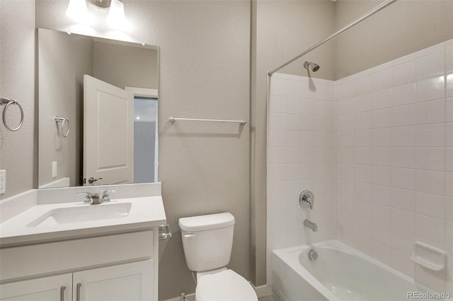 full bathroom featuring tiled shower / bath, vanity, and toilet