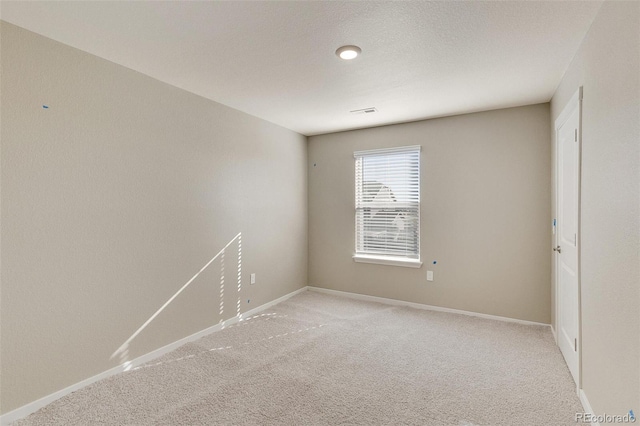 spare room with light carpet and a textured ceiling