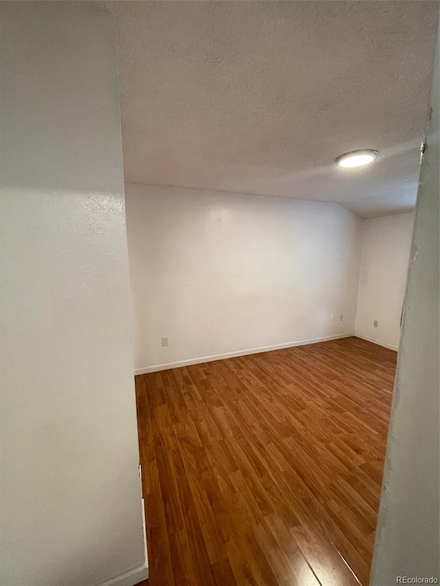 unfurnished room featuring a textured ceiling and dark hardwood / wood-style floors