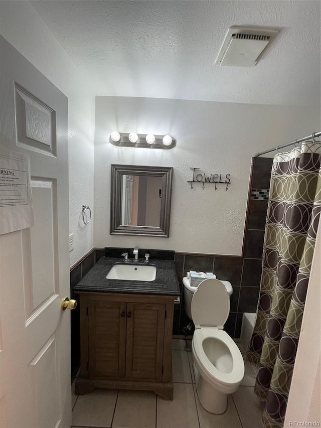 full bathroom with tile flooring, tile walls, toilet, vanity, and shower / tub combo with curtain