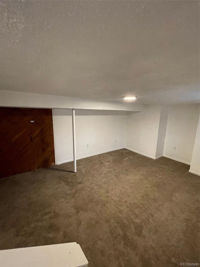 basement with dark colored carpet and a textured ceiling