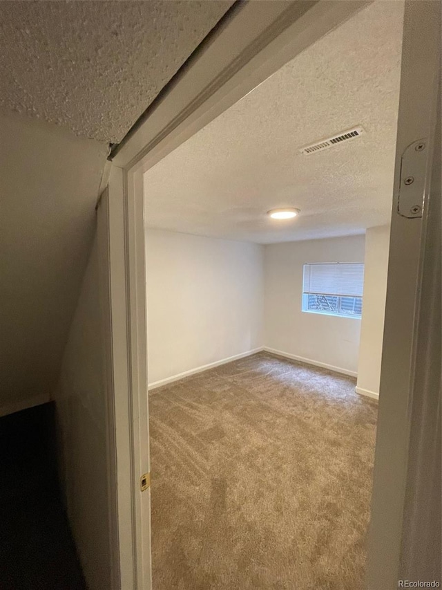 carpeted empty room with a textured ceiling