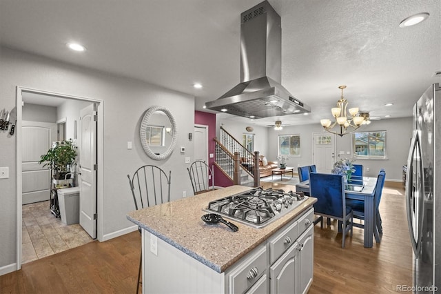 4942 Grove St, Denver, CO 80221 - kitchen with appliances with stainless steel finishes, dark wood-style flooring, island exhaust hood, and ceiling fan with notable chandelier