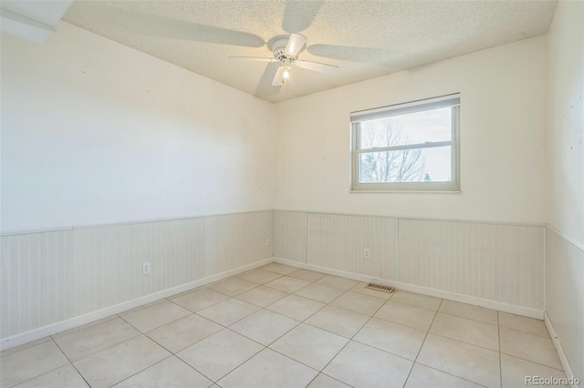 18 Clover Cir, Colorado Springs, CO 80906 - tiled empty room with a wainscoted wall, ceiling fan, and a textured ceiling