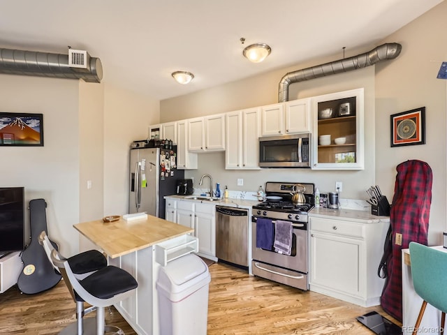 1441 Central Unit 305, Denver, CO 80211 - kitchen featuring stainless steel appliances, light wood-style floors, white cabinets, and a kitchen bar