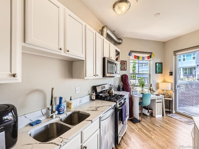 1441 Central Unit 305, Denver, CO 80211 - kitchen featuring appliances with stainless steel finishes, white cabinetry, light wood-style flooring, light stone counters, and an office area